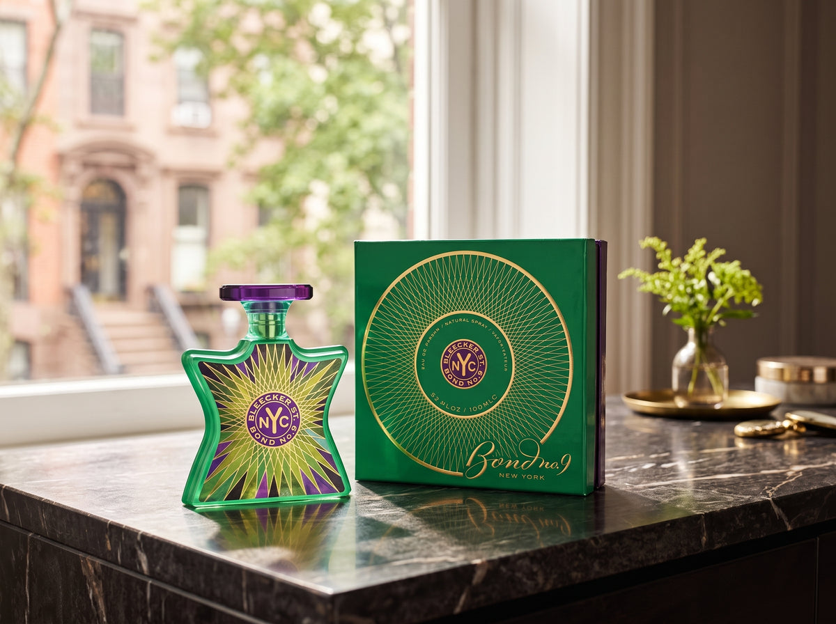 A green star-shaped perfume bottle with a purple and yellow sunburst design stands beside a matching green rectangular box with gold circular linework and the text 'Benoït No. 9' on a dark marble countertop near a window.