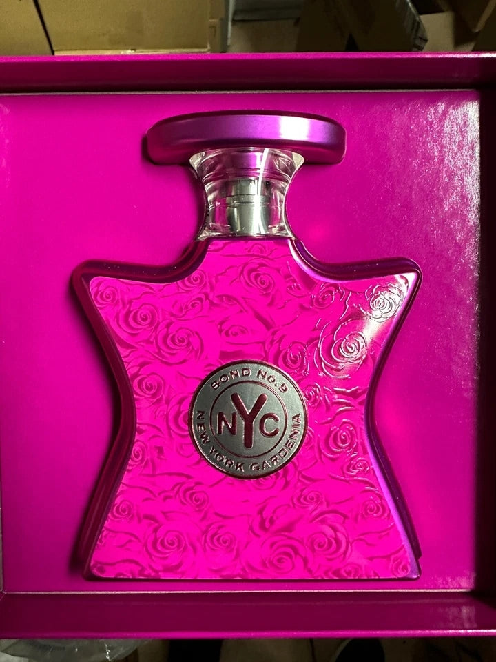 A pink Bondo NYC perfume bottle with a rose-patterned body and a silver circular logo medallion, presented inside a bright pink gift box.