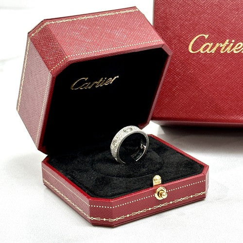 A Cartier ring displayed inside an open red jewelry box with black velvet lining, with a matching red Cartier box in the background.