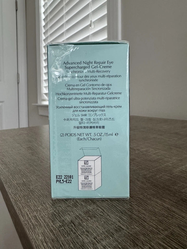 The back of a light blue box for Advanced Night Repair Eye Supercharged Gel-Creme, placed on a wooden table in front of a window with blinds.