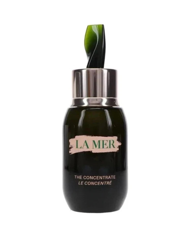La Mer The Concentrate Le Concentrée bottle in dark green glass with a silver dropper cap and a green leaf-shaped dropper tip, on a white background.