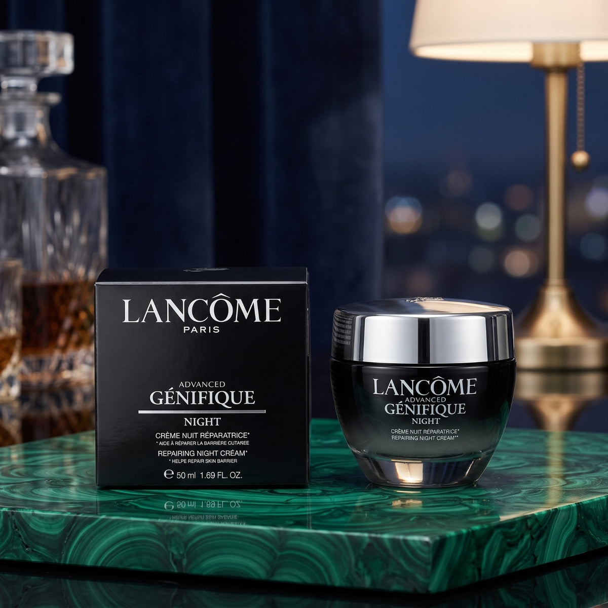 Lancôme Paris Advanced Genifique Night cream jar and its black retail box, displayed on a green marbled surface with a dark blue curtain and a lamp in the background.