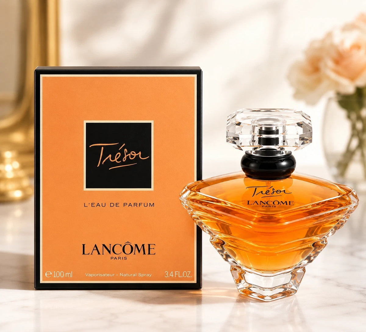 Lancôme Téléphon L'EAU DE PARFUM perfume bottle and its orange packaging box, displayed on a light marble surface with soft-focus flowers in the background.
