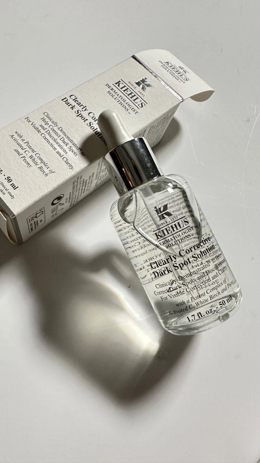Kiehl's Clear Skin Clearing Dark Spot Remover serum bottle with dropper next to its white cardboard packaging box on a light gray surface.