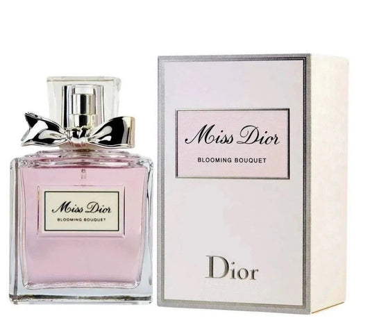 Dior Miss Dior Blooming Bouquet perfume bottle with a silver bow on a clear glass base, shown next to its white and silver packaging box.