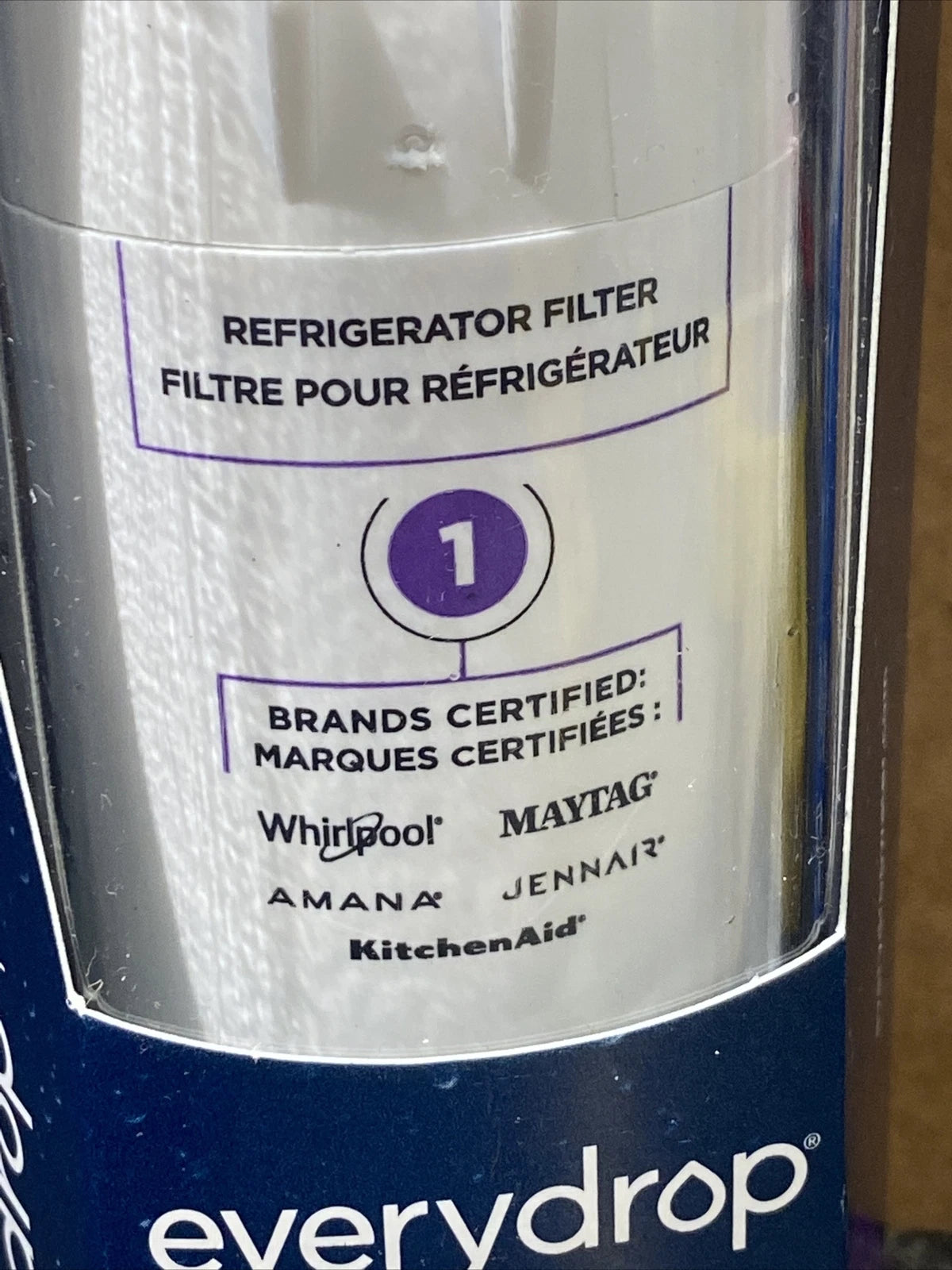 A close-up of a refrigerator filter canister by everydrop, showing a white label with purple text and logos for certified brands including Whirlpool, Maytag, Amana, Jennair, and KitchenAid.